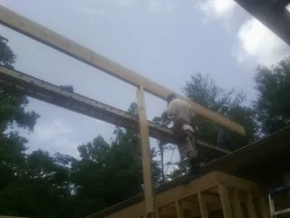 Carpenter setting a ridge beam over a new addition frame — Ice Dam Removal by Roofing Brothers in Corry