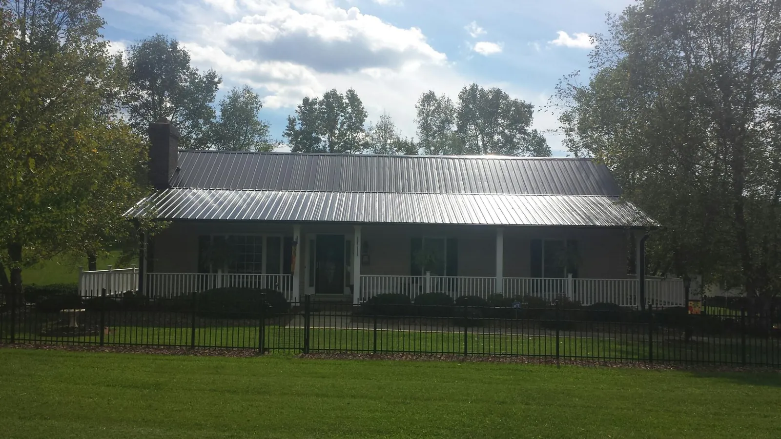 Gray metal roof on a brick ranch with a full width front porch — Gutter Guard Installation work by our crew in Corry