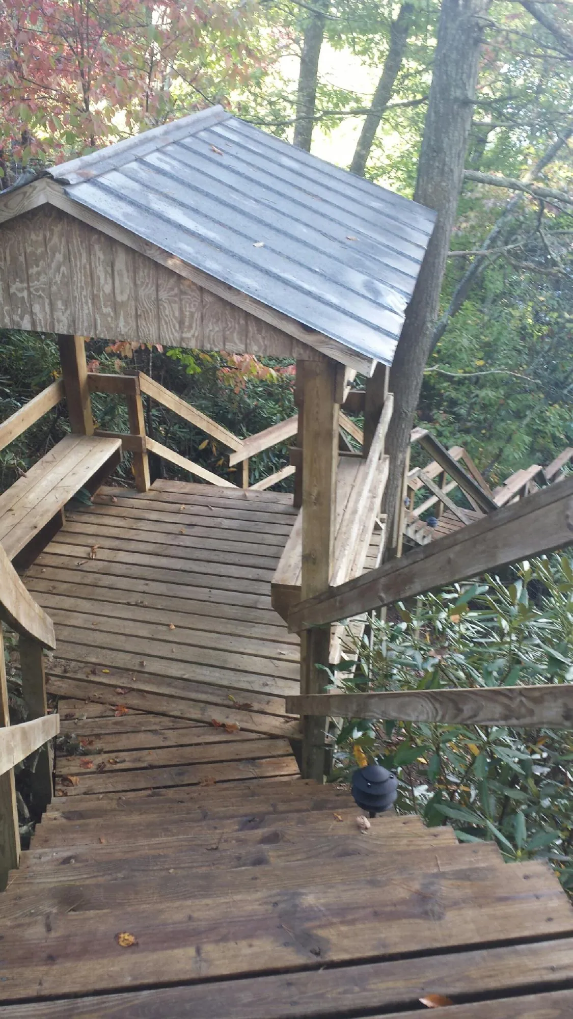Metal roofed shelter over wooden steps on a wooded walkway — Skylight Repair & Installation work by our crew in Corry